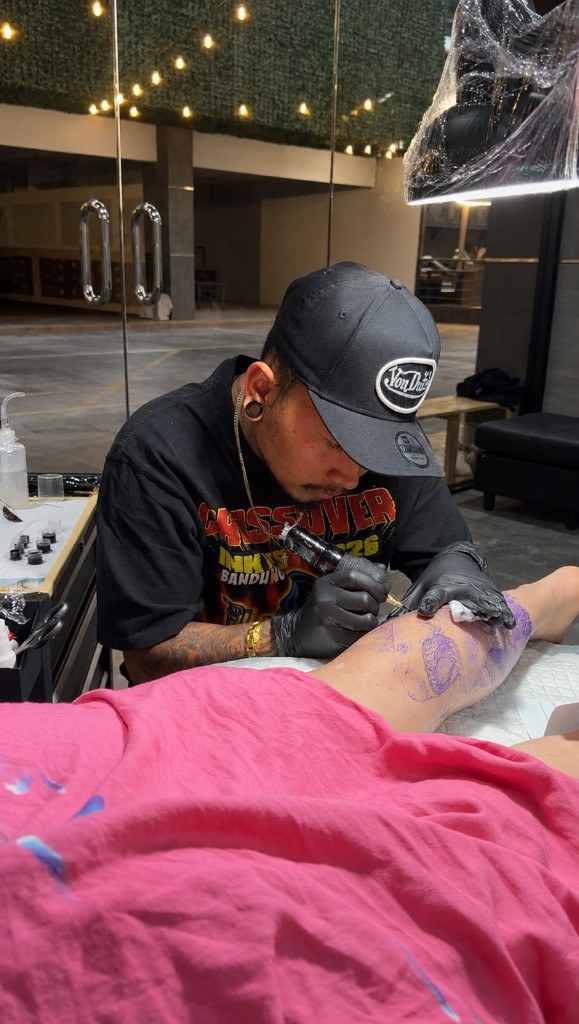 Tattoo artist working on a client leg stencil in the studio