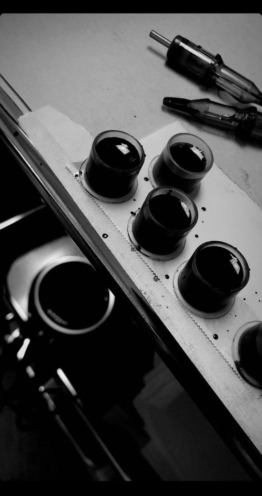 Black and white close-up of ink caps and tattoo cartridges